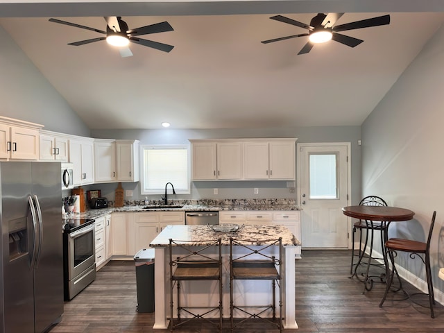 kitchen featuring a ceiling fan, a sink, light stone counters, appliances with stainless steel finishes, and dark wood-style flooring