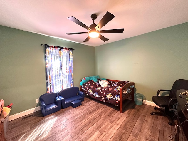 bedroom with wood finished floors, visible vents, and baseboards