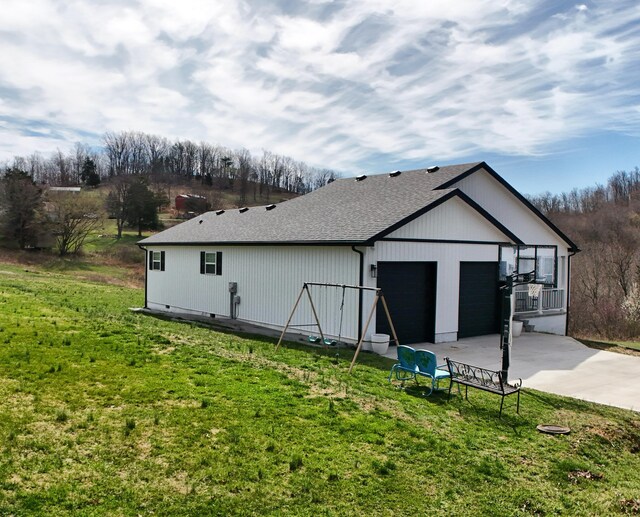exterior space with a lawn, driveway, a shingled roof, and a garage