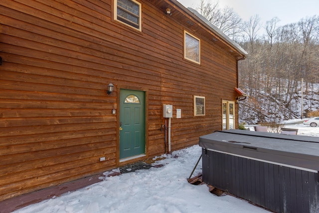 snow covered house featuring a hot tub