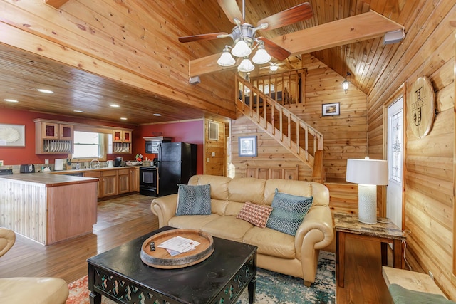 living room featuring vaulted ceiling with beams, wood ceiling, wooden walls, and light wood-type flooring