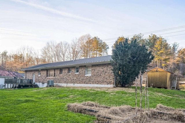 back of property with a storage unit, central AC unit, a deck, and a lawn