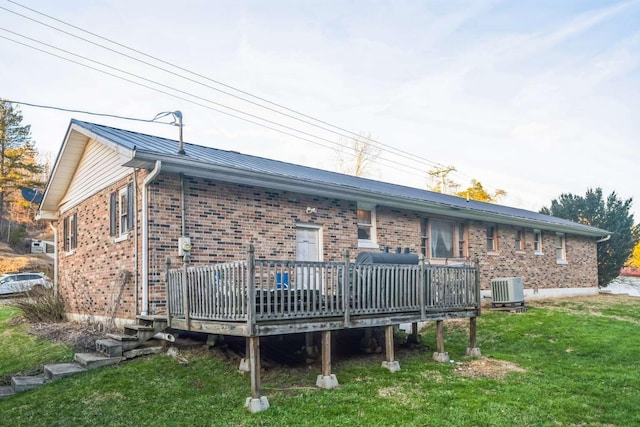 back of house featuring central AC, a deck, and a lawn