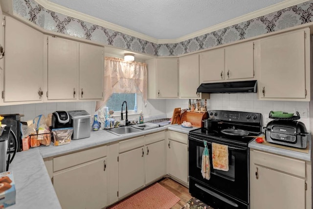 kitchen with black range with electric stovetop, cream cabinets, sink, and a textured ceiling