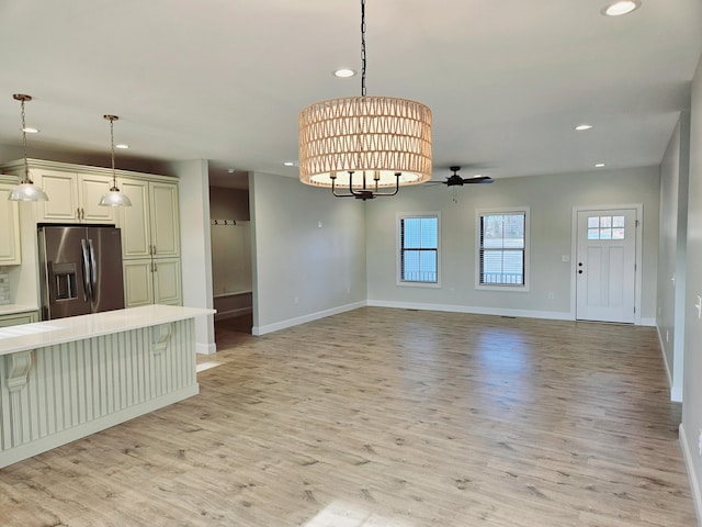 interior space featuring open floor plan, light countertops, stainless steel refrigerator with ice dispenser, and decorative light fixtures