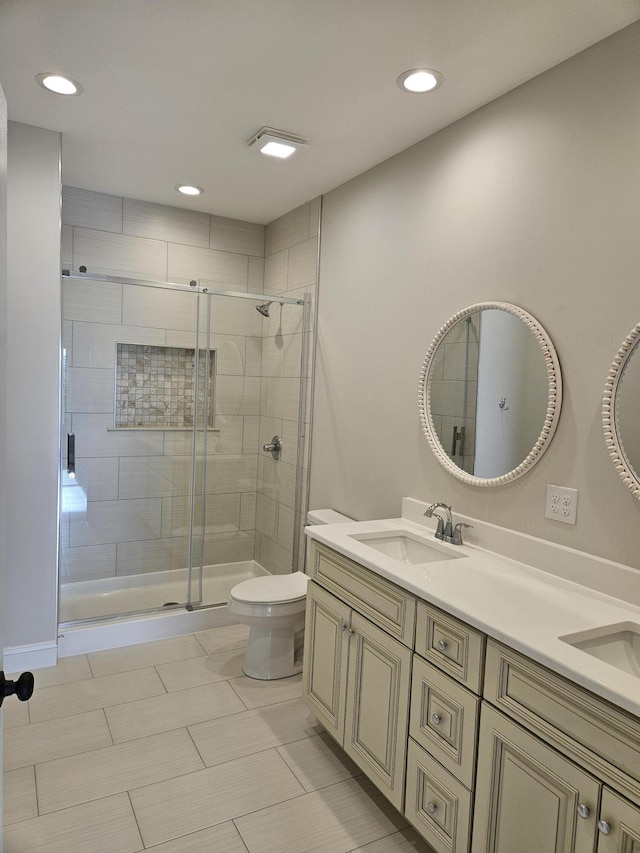 full bathroom featuring toilet, a stall shower, double vanity, and a sink