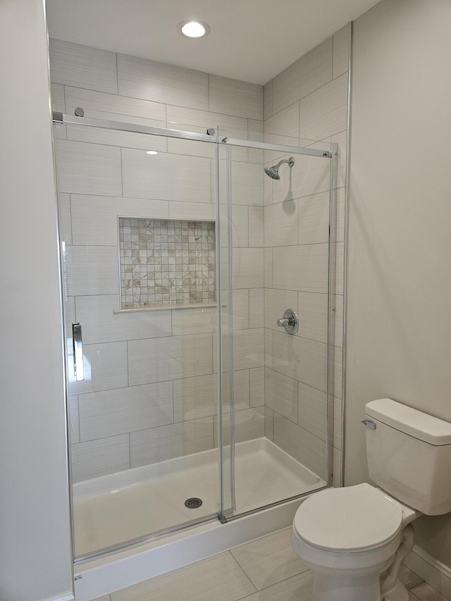 full bathroom with a stall shower, baseboards, toilet, and tile patterned floors