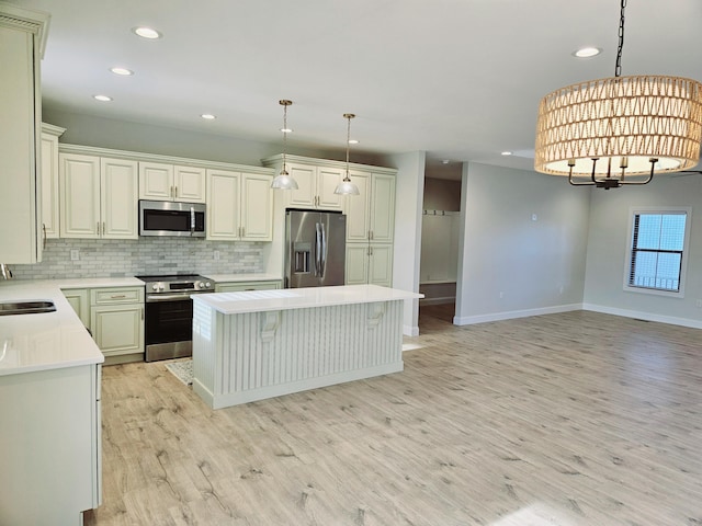 kitchen with stainless steel appliances, a center island, light countertops, and decorative light fixtures