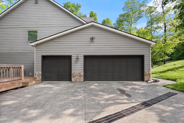 view of side of home featuring stone siding, concrete driveway, and a yard