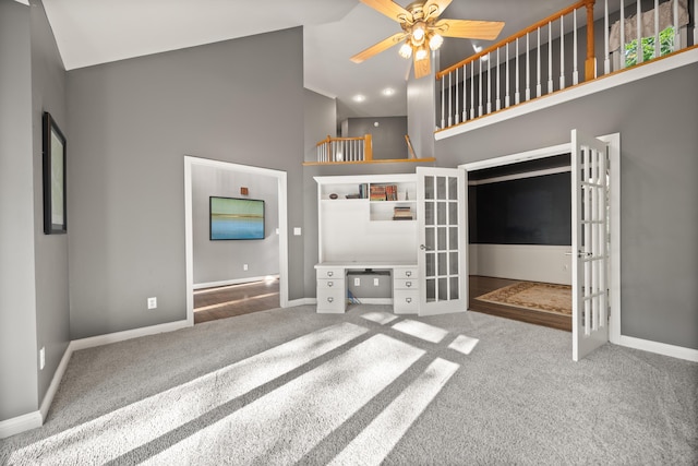 unfurnished living room featuring french doors, high vaulted ceiling, carpet floors, baseboards, and ceiling fan