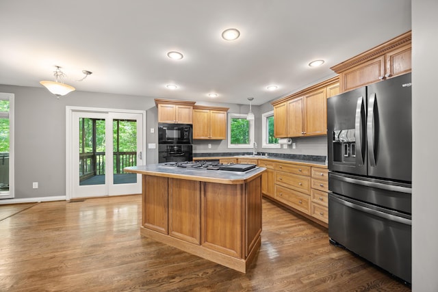 kitchen featuring black appliances, healthy amount of natural light, wood finished floors, a sink, and recessed lighting