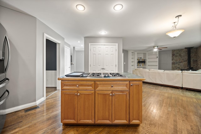kitchen featuring stainless steel appliances, a ceiling fan, dark wood-type flooring, built in features, and brown cabinetry