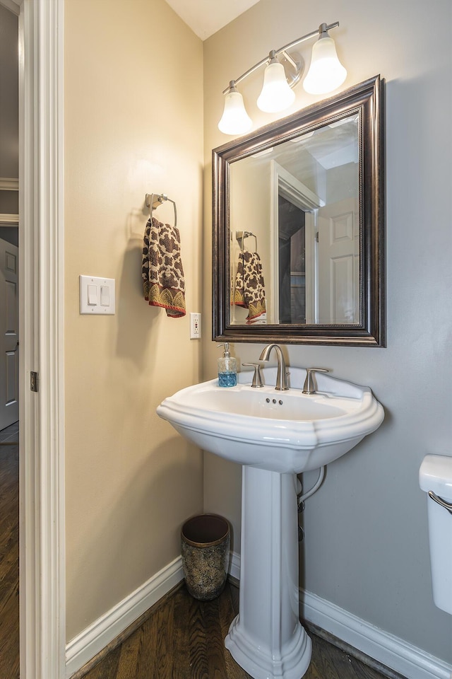 bathroom featuring baseboards, wood finished floors, and toilet