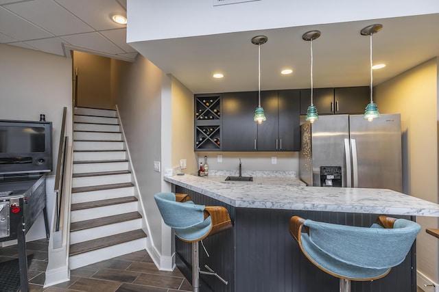 kitchen featuring stainless steel fridge, a breakfast bar area, light countertops, pendant lighting, and wood finish floors