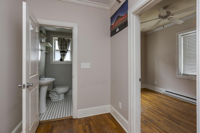 bathroom featuring crown molding, wood-type flooring, toilet, and baseboard heating