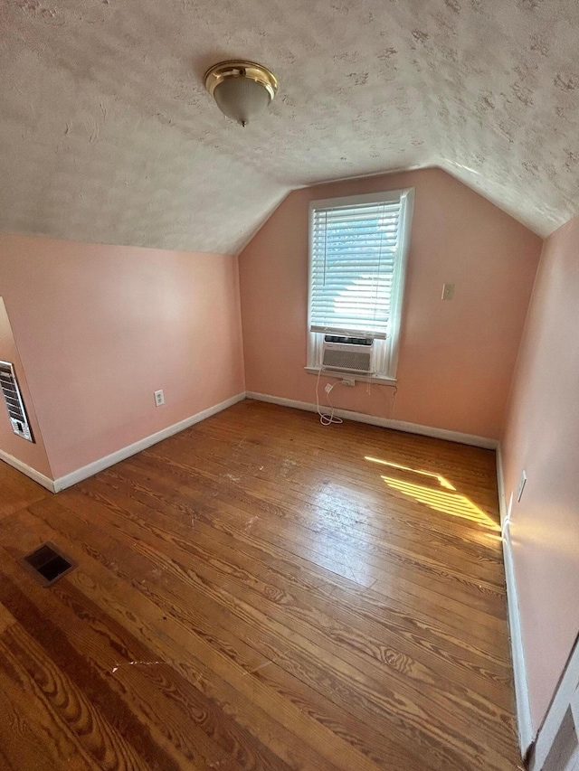 bonus room with cooling unit, wood-type flooring, lofted ceiling, and a textured ceiling