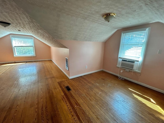 bonus room with lofted ceiling, hardwood / wood-style floors, cooling unit, and a textured ceiling