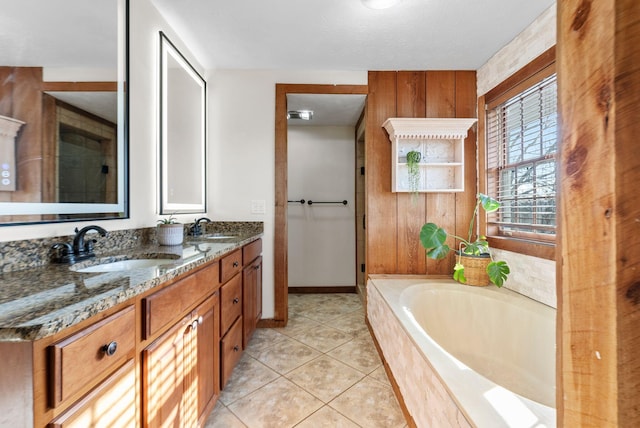 bathroom with tiled bath, tile patterned flooring, wood walls, and vanity