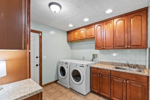 laundry room with washing machine and clothes dryer, sink, cabinets, and a textured ceiling