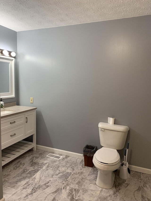 half bathroom featuring a textured ceiling, vanity, visible vents, marble finish floor, and baseboards