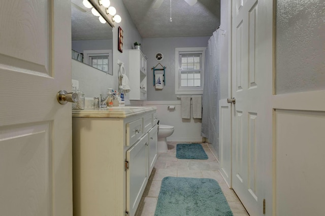 bathroom with vanity, toilet, tile patterned flooring, and a textured ceiling