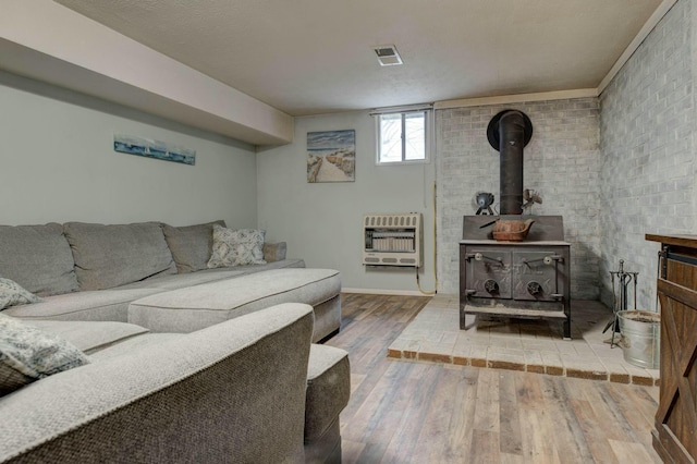 living room featuring heating unit, hardwood / wood-style floors, and a wood stove