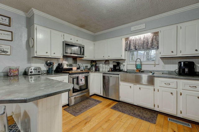 kitchen featuring white cabinetry, appliances with stainless steel finishes, kitchen peninsula, and sink