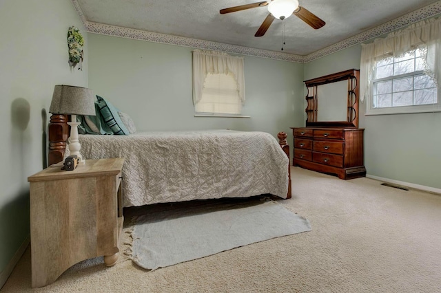 carpeted bedroom featuring ceiling fan and a textured ceiling