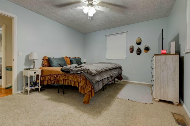 bedroom with ceiling fan, carpet floors, and a textured ceiling