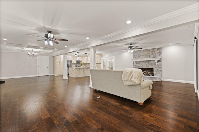 living room with ceiling fan with notable chandelier, a fireplace, decorative columns, ornamental molding, and dark wood-type flooring