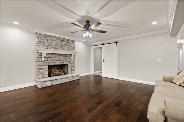 unfurnished living room featuring a fireplace, crown molding, hardwood / wood-style flooring, ceiling fan, and a barn door