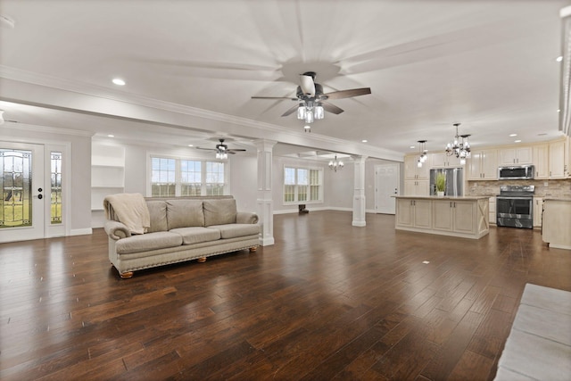 living room with dark hardwood / wood-style flooring, ceiling fan with notable chandelier, ornamental molding, and decorative columns