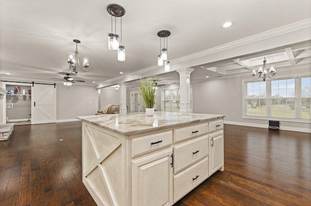 kitchen featuring ceiling fan with notable chandelier, a center island, light stone countertops, decorative light fixtures, and a barn door