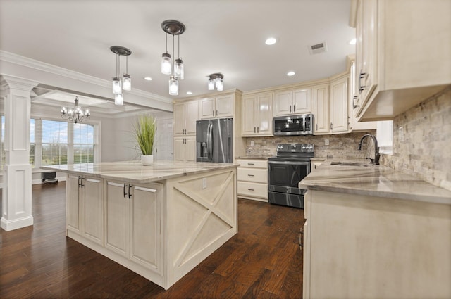 kitchen featuring a kitchen island, hanging light fixtures, light stone counters, stainless steel appliances, and cream cabinetry