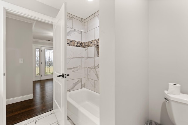 bathroom with ornamental molding, toilet, tiled shower / bath combo, and hardwood / wood-style floors