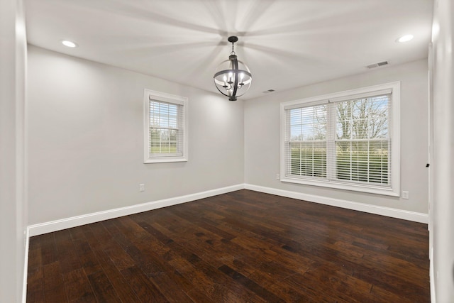 empty room featuring a notable chandelier and dark hardwood / wood-style flooring