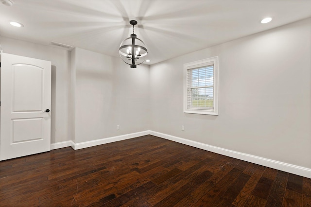 unfurnished room with a notable chandelier and dark wood-type flooring