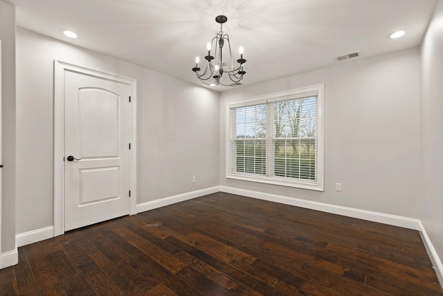 spare room with an inviting chandelier and dark hardwood / wood-style floors