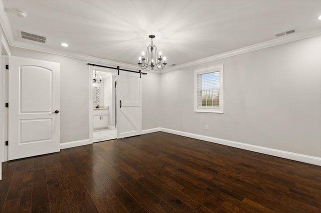 empty room with crown molding, a barn door, dark wood-type flooring, and a chandelier