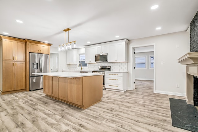 kitchen with white cabinetry, stainless steel appliances, decorative light fixtures, and a kitchen island