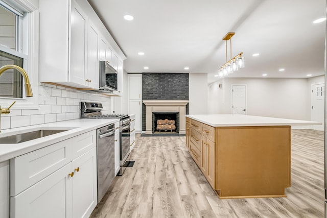 kitchen featuring sink, appliances with stainless steel finishes, hanging light fixtures, a center island, and white cabinets