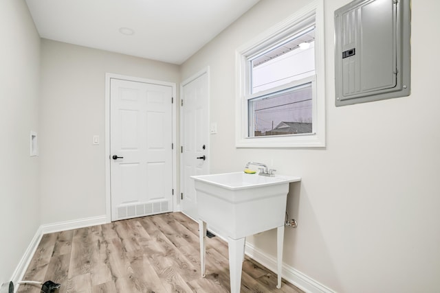 laundry area featuring electric panel and light hardwood / wood-style floors