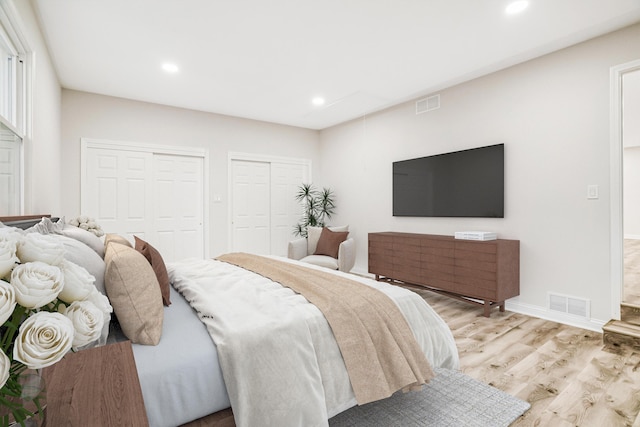 bedroom featuring light hardwood / wood-style floors and multiple closets