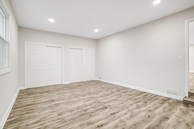 unfurnished bedroom with multiple closets and light hardwood / wood-style floors