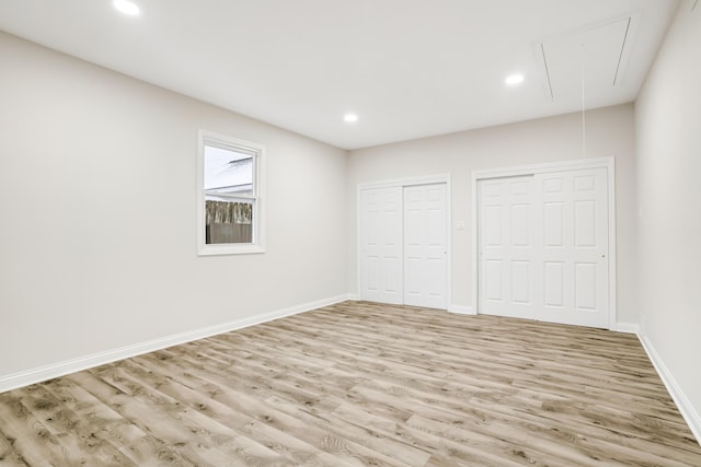 unfurnished bedroom featuring multiple closets and light hardwood / wood-style flooring