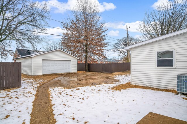 snowy yard featuring a garage, an outdoor structure, and central AC unit