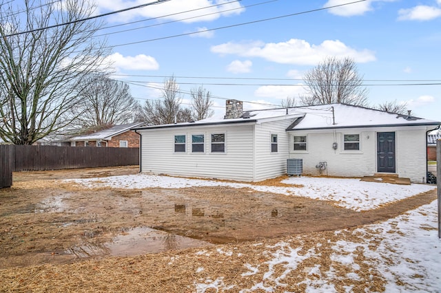 snow covered rear of property featuring central AC