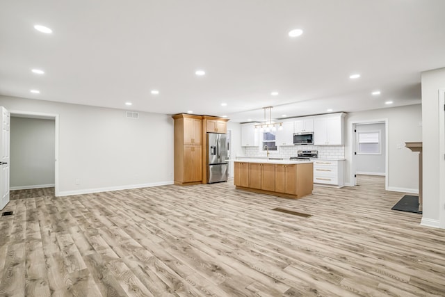 kitchen with stainless steel appliances, a center island, decorative backsplash, white cabinets, and decorative light fixtures