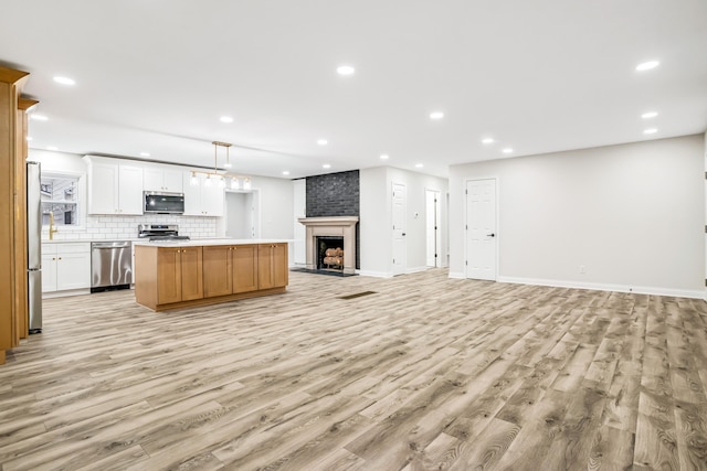 kitchen with decorative light fixtures, a center island, stainless steel appliances, decorative backsplash, and white cabinets