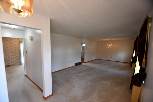 carpeted empty room featuring a chandelier